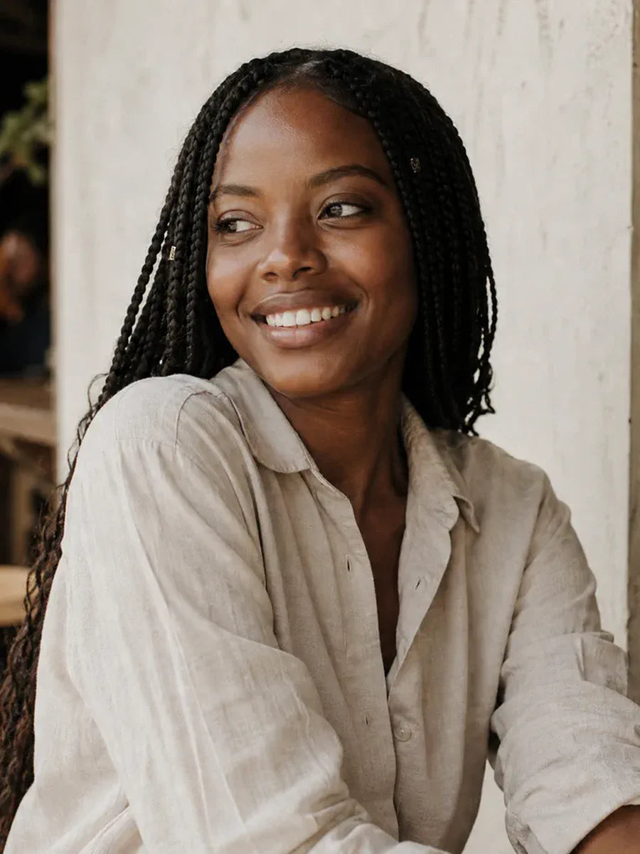 Illustrative woman with braids at a cafe, accompanying a human-versus-synthetic buying note.